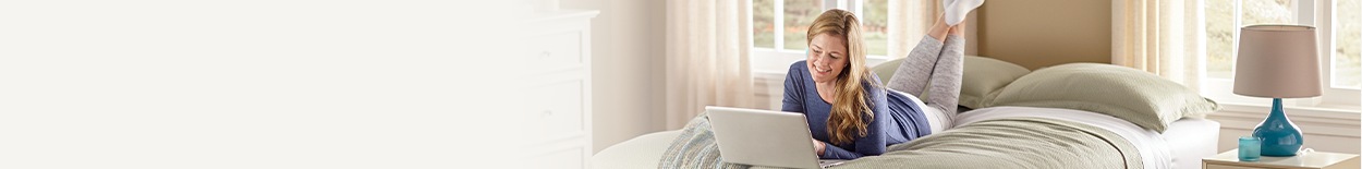 Girl with laptop lounging on a bed